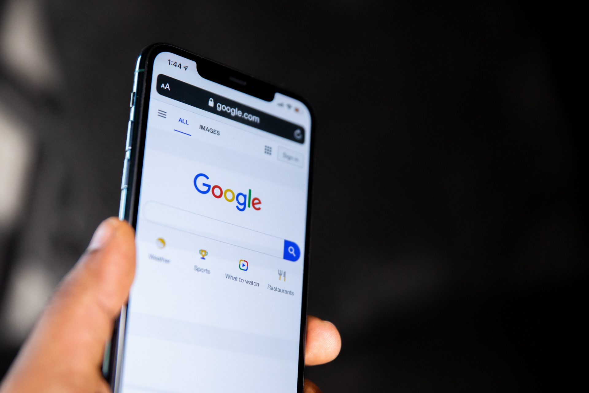 Un smartphone saisis par une main et affichant une page Google