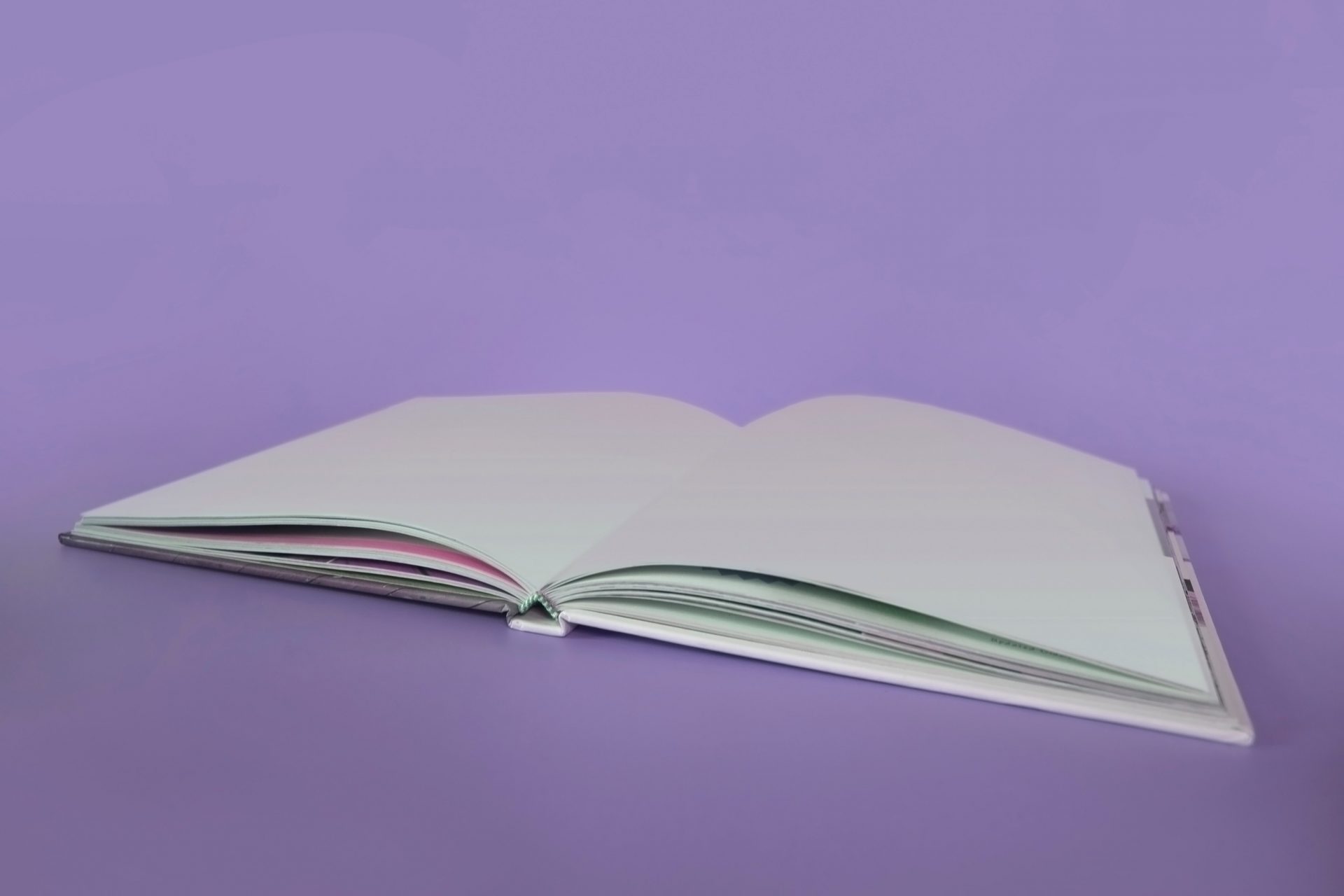 Livre ouvert sur deux pages blanches sur un fond violet